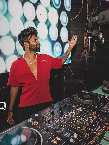 Posing by the decks at Freq Club, with the club's logo and a vibrant LED background.