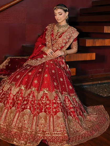 The classic red bridal lehenga is iconic, and my goal is to make it uniquely yours. Here, I focused on creating a regal silhouette, draping the rich fabric to highlight the exquisite gold embroidery. The look is completed with layered traditional jewelry, crafting a portrait of a timeless, royal bride.
