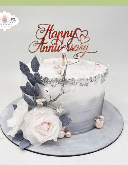 A sophisticated silver and grey anniversary cake, adorned with delicate sugar flowers and silver leaf.