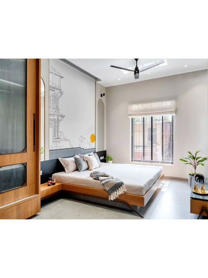 A minimalist bedroom design with a low platform bed and a custom wooden wardrobe with fluted glass panels.