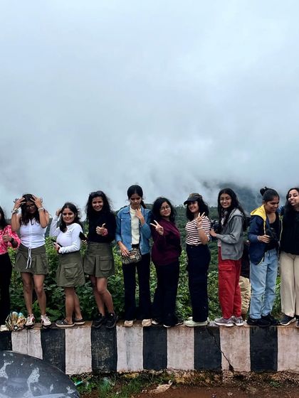 A fun group photo on a wall with the misty hills of Chikmagalur in the background.