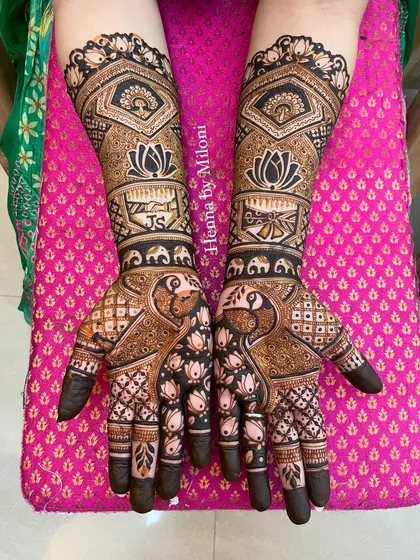 A beautifully detailed bridal mehendi with a mix of everything. It includes peacocks, elephants, lotus flowers, and personalized initials, all tied together with fine checkerboard patterns and bold borders.