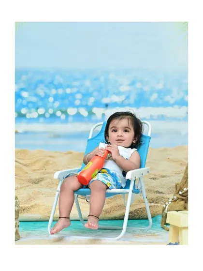 This little guy is relaxing in a blue deck chair, looking like he's ready for a nap by the ocean. The indoor beach theme is perfect for creating relaxed and playful baby portraits.