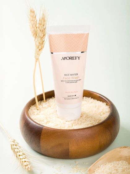 A rice water face wash styled in a wooden bowl filled with rice grains. Using key ingredients as props is a great way to visually communicate the product's formula.