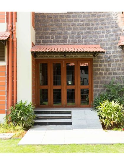 A close-up of an entrance, where the warmth of the wooden door and tiled awning contrasts beautifully with the cool texture of the stone wall.