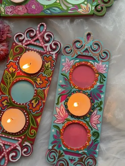 Two of our new three-set tea light holders, one with a floral design and one with a folk-art style.