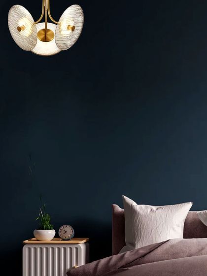 The same disc pendant used as a bedside light against a dark wall. The warm glow creates a cozy, intimate atmosphere, perfect for a modern bedroom.