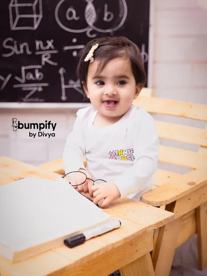 A big, happy smile from our little scholar. The details of the 'back to school' theme, like the tiny glasses, make this first birthday shoot so memorable.