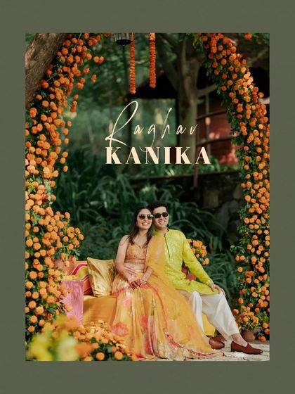 A portrait of the couple seated under a marigold arch, a classic and beautiful Haldi setup.