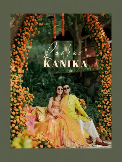 A classic Haldi portrait of the couple sitting together, surrounded by a beautiful arch of marigold flowers.