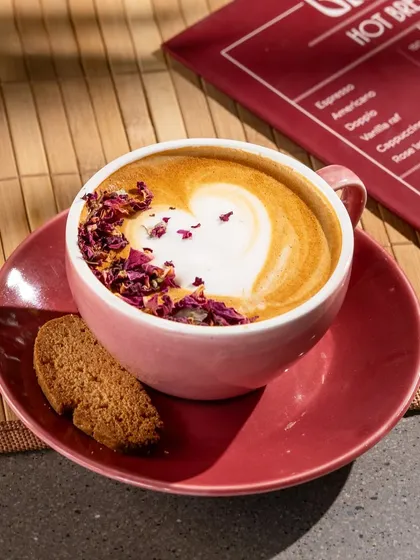 A rose latte from Grid, with the menu visible in the background. This is a practical shot for showcasing a specific menu item.