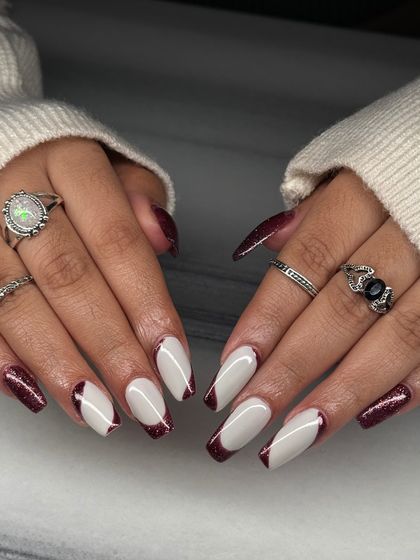 A dramatic and edgy take on the French manicure. This set features a sharp, angled French tip using a deep red glitter, paired with a solid white base.