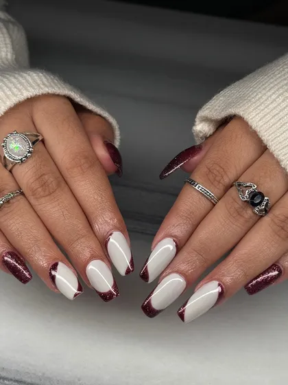 A dramatic and edgy take on the French manicure. This set features a sharp, angled French tip using a deep red glitter, paired with a solid white base.