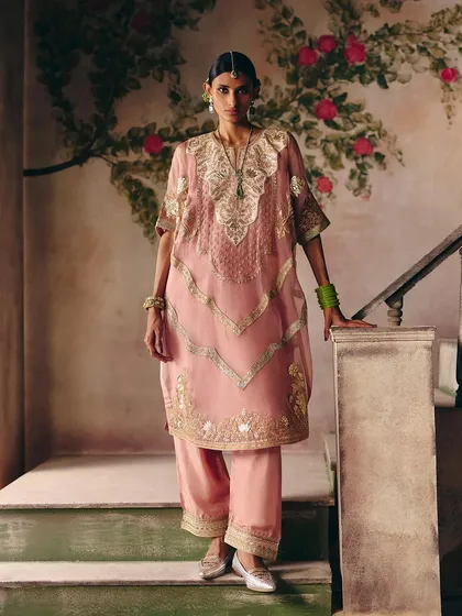 A beautiful moment on the stairs. This model wears a dusty pink kurta set with delicate gold embroidery, showcasing a look of timeless elegance.