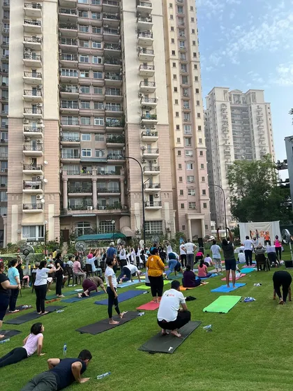 A wide shot of the International Yoga Day event, with dozens of participants moving together on the lawn. The collective energy of a community practicing in unison is truly powerful.