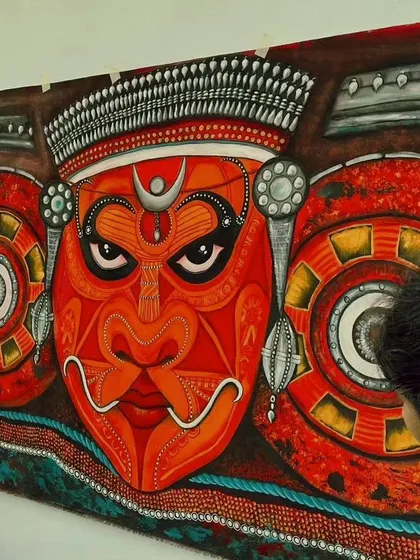 A close-up view of the Theyyam painting, highlighting the textures and the fierce, divine expression in the eyes.