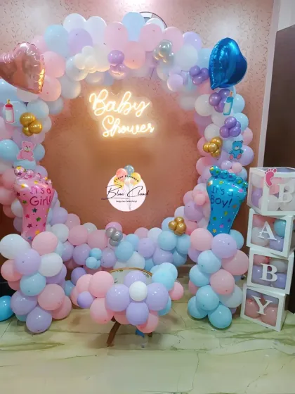 A gender reveal baby shower setup with a heart-shaped balloon frame and 'It's a Girl' and 'It's a Boy' foil balloons.