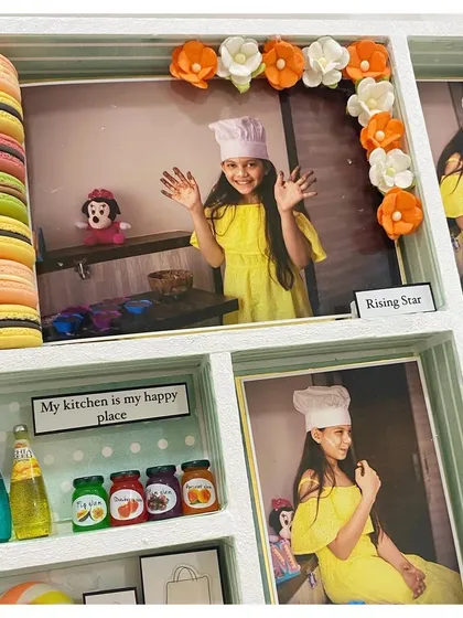 A section of the frame showing the 'Rising Star' with a tower of colorful macarons and a garland of paper flowers.