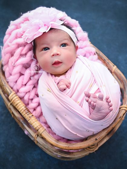 This baby girl is awake and making eye contact, her bright eyes being the focus of this lovely portrait in a pink-themed basket setup.