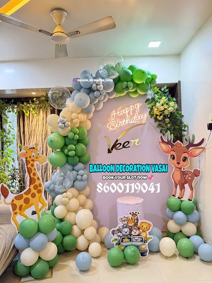 A soft and sweet jungle theme for Veer's birthday. This setup uses a pastel color palette of green, blue, and white, with cute giraffe and deer cutouts.