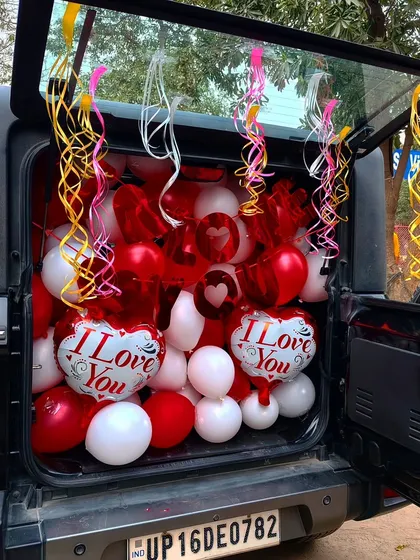 If you want a surprise that's different, I can do a car boot decoration. I fill the car boot with balloons and ribbons, like this red and white 'I Love You' theme, so you can reveal the surprise anywhere you like.