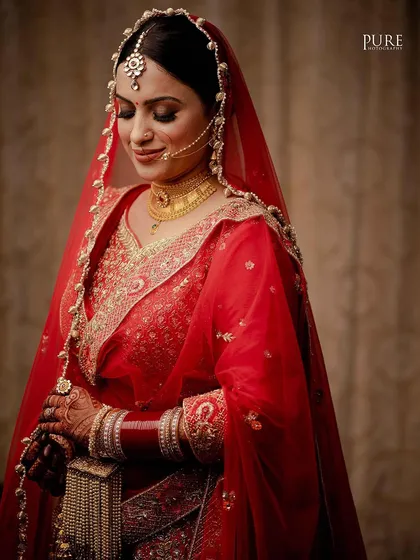 A classic bridal portrait capturing the bride's serene beauty and the elegance of her red wedding dupatta and traditional jewelry.