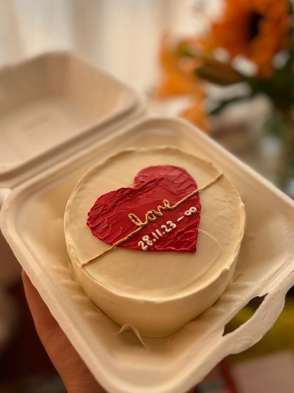 This anniversary bento cake features a textured red heart with the couple's special date and an infinity symbol, all hand-piped.