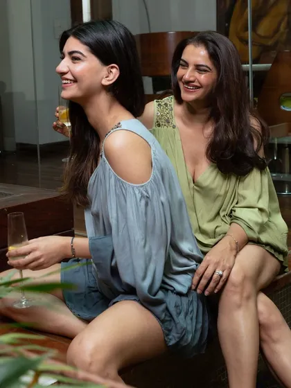 A candid moment captured between two models in stylish wrap-over dresses, laughing together. This photo creates an authentic, relatable feel for a lifestyle brand campaign.