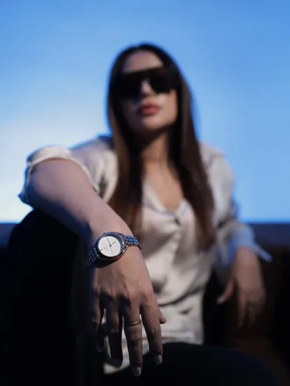 A focused shot on a classic silver watch, elevating a simple satin shirt and black trousers.