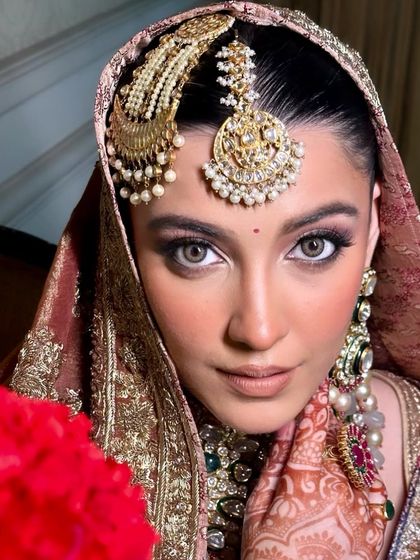 A captivating close-up of a bride with striking eyes. The makeup is focused on defining her eyes while keeping the rest of the look soft and traditional, complemented by a stunning passapatti.