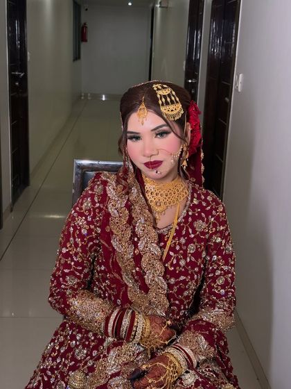 A seated portrait of the bride. Her makeup is perfectly balanced, with bold lips and defined eyes that complement her traditional attire.