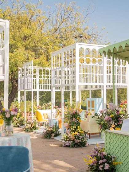 A wide shot of the brunch area, showcasing the multiple trellis lounges and the beautifully landscaped garden.