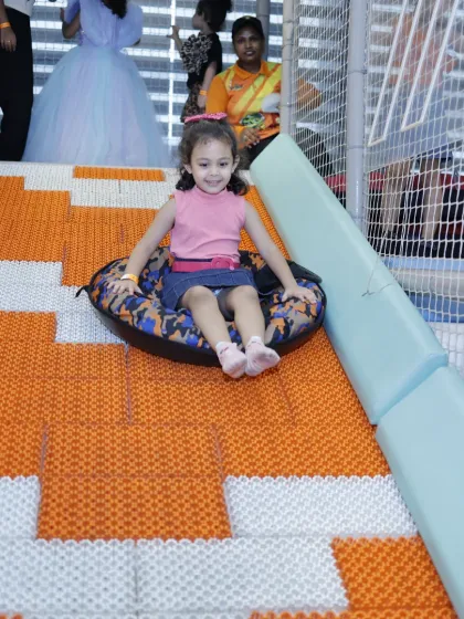 The doughnut slide is fun for all ages. A young girl smiles as she slides down on the inflatable tube.