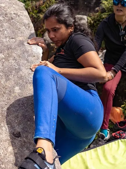 A climber receives guidance from a spotter as she navigates a tricky sequence.