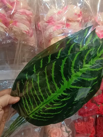 A large, realistic-looking artificial leaf. I stock a wide variety of artificial foliage that can be used to create lush, green backdrops for any event.