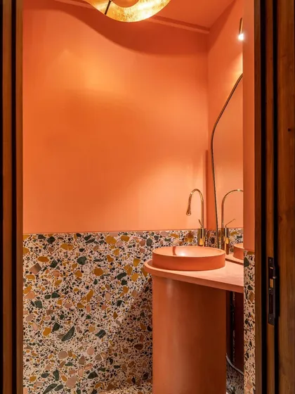 Even a small powder room can make a big statement. We designed this space with a custom concrete pedestal basin and vibrant pink walls, complemented by terrazzo flooring and brass fixtures. It’s a playful and unexpected moment of bold design.