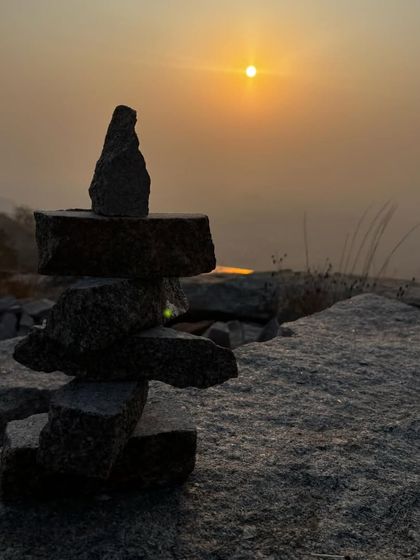 A stack of balanced stones against the rising sun. A moment of zen and creativity on the hilltop.
