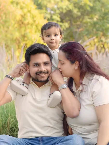 A tender moment between mother and father, while their child enjoys a ride on dad's shoulders.