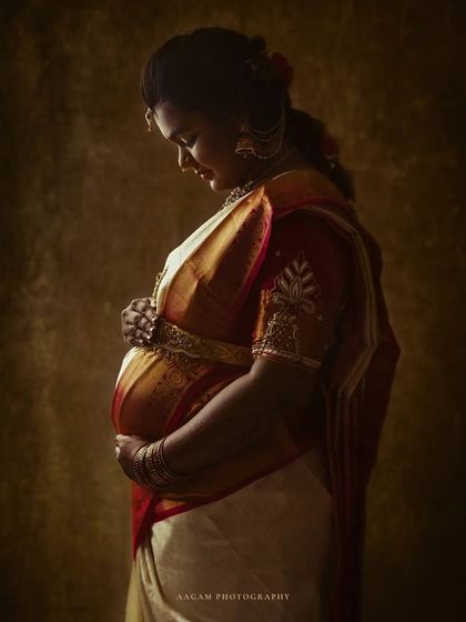 A close-up, painterly portrait of a mother-to-be in a traditional silk saree. The focus on the rich fabric and her gentle hands tells a story of heritage and love.