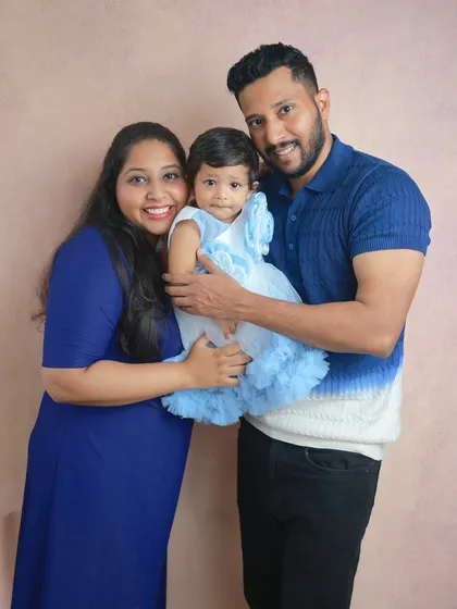 A classic family portrait against a warm, neutral backdrop. Everyone is smiling at the camera, creating a beautiful, timeless image that is perfect for framing and sharing with loved ones.