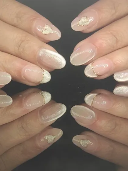 A delicate French manicure featuring a subtle white cat-eye effect on the tips and tiny gold bead accents.