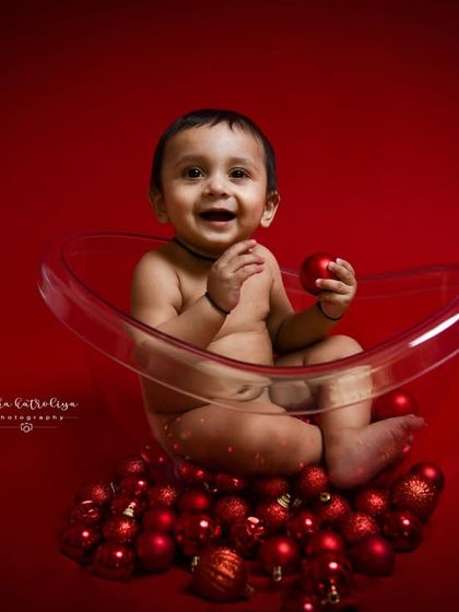 This shot captures the baby's curiosity as he plays with one of the red baubles. These simple, interactive moments make for wonderful and authentic baby portraits.