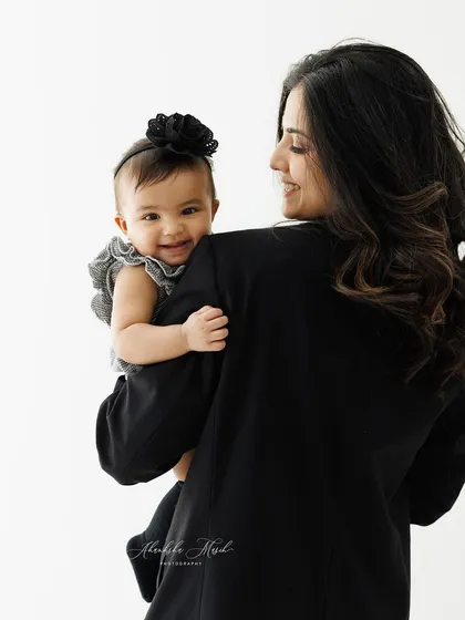 A sweet moment captured over the shoulder. The baby's bright smile and the mother's loving gaze create a candid and heartwarming portrait of their special connection.