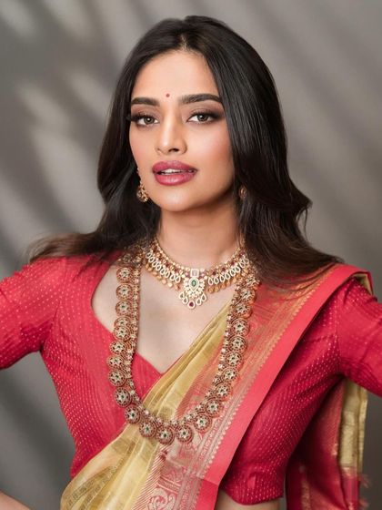 A classic South Indian bridal portrait with a focus on the jewelry and makeup. The lighting is carefully controlled to bring out the warm tones of the silk saree and the sparkle of the gold.