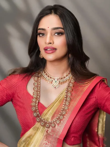 A classic South Indian bridal portrait with a focus on the jewelry and makeup. The lighting is carefully controlled to bring out the warm tones of the silk saree and the sparkle of the gold.