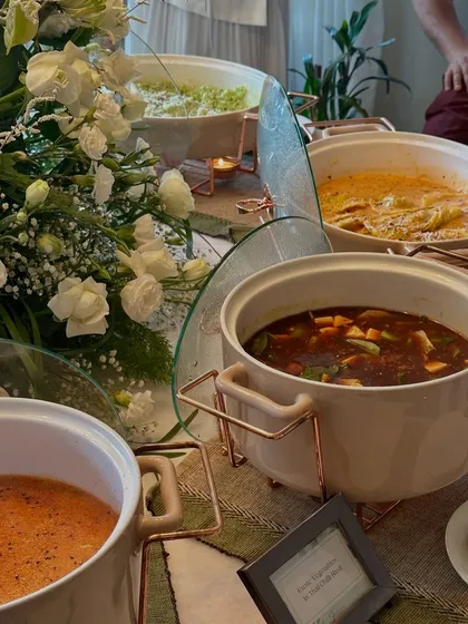 A wide shot of our buffet setup, featuring a mix of Italian and Asian main courses in elegant serving dishes, surrounded by white floral arrangements.