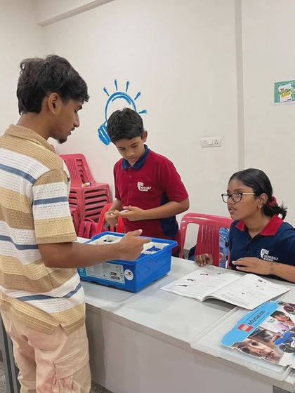 An instructor provides one-on-one guidance to students at Vidyashilp Academy, ensuring they understand the building techniques for their robotics project.