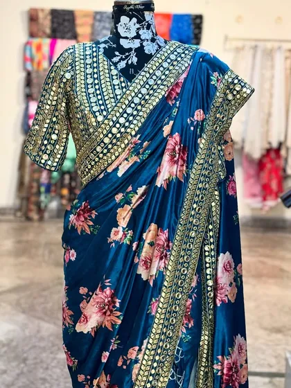 A closer look at the 'NIKHAAR' saree. The combination of the deep teal floral fabric and the heavy mirror work blouse creates a look that is both elegant and festive.
