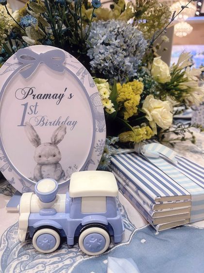 Every detail is considered, from the personalized stationery to the miniature train table decor, all in the party's blue and white color scheme.
