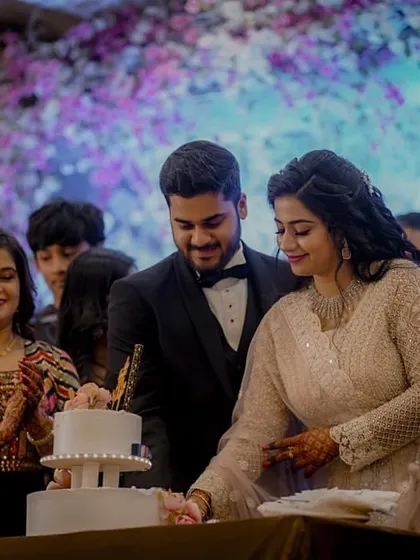 The couple cuts their beautiful two-tiered engagement cake together, surrounded by the applause and happy faces of their family.